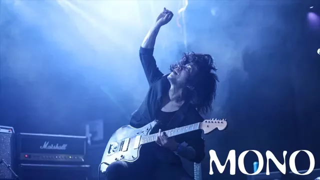 Musician performing on stage with electric guitar under blue dramatic lighting